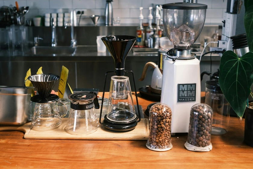 A wooden table topped with coffee cups and a blender